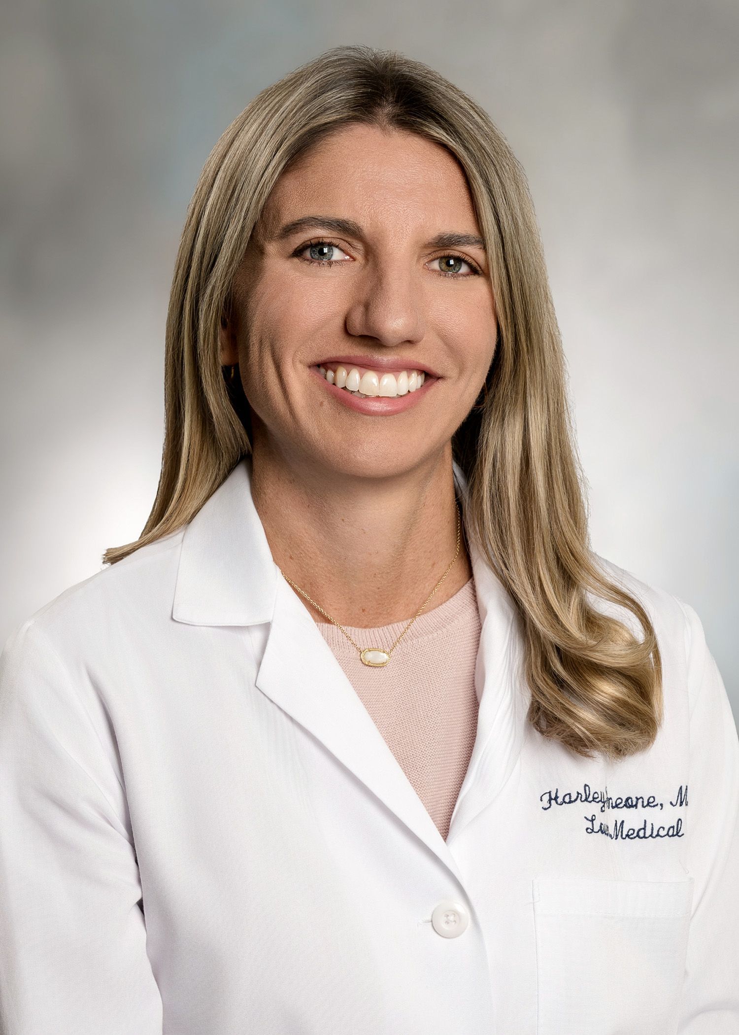 A woman in a white lab coat is smiling for the camera.