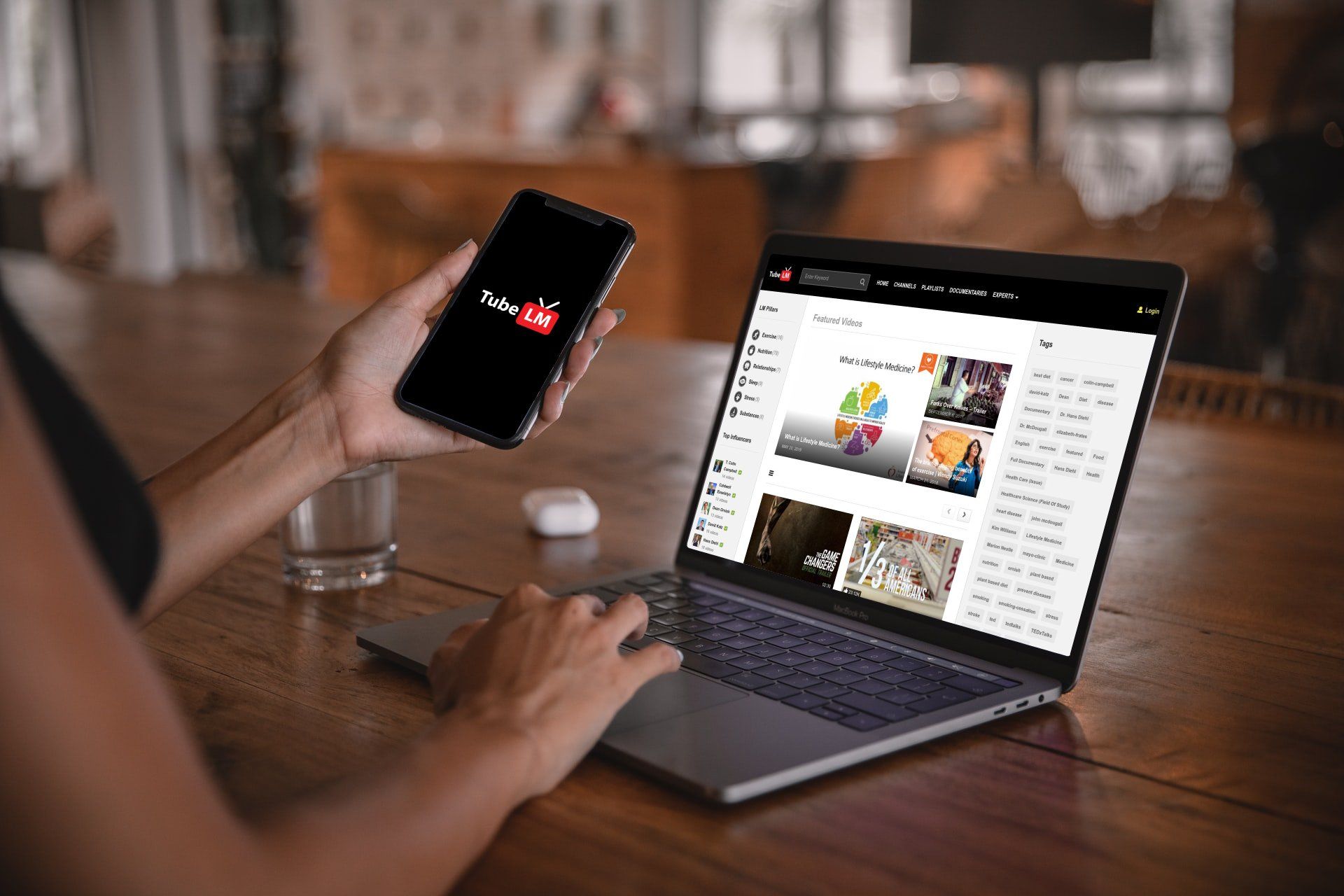 A person is holding a cell phone in front of a laptop computer.