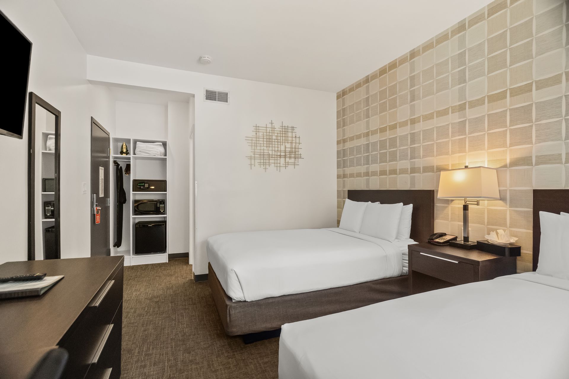 Spacious hotel guest room with queen bed, open closet area, and contemporary design