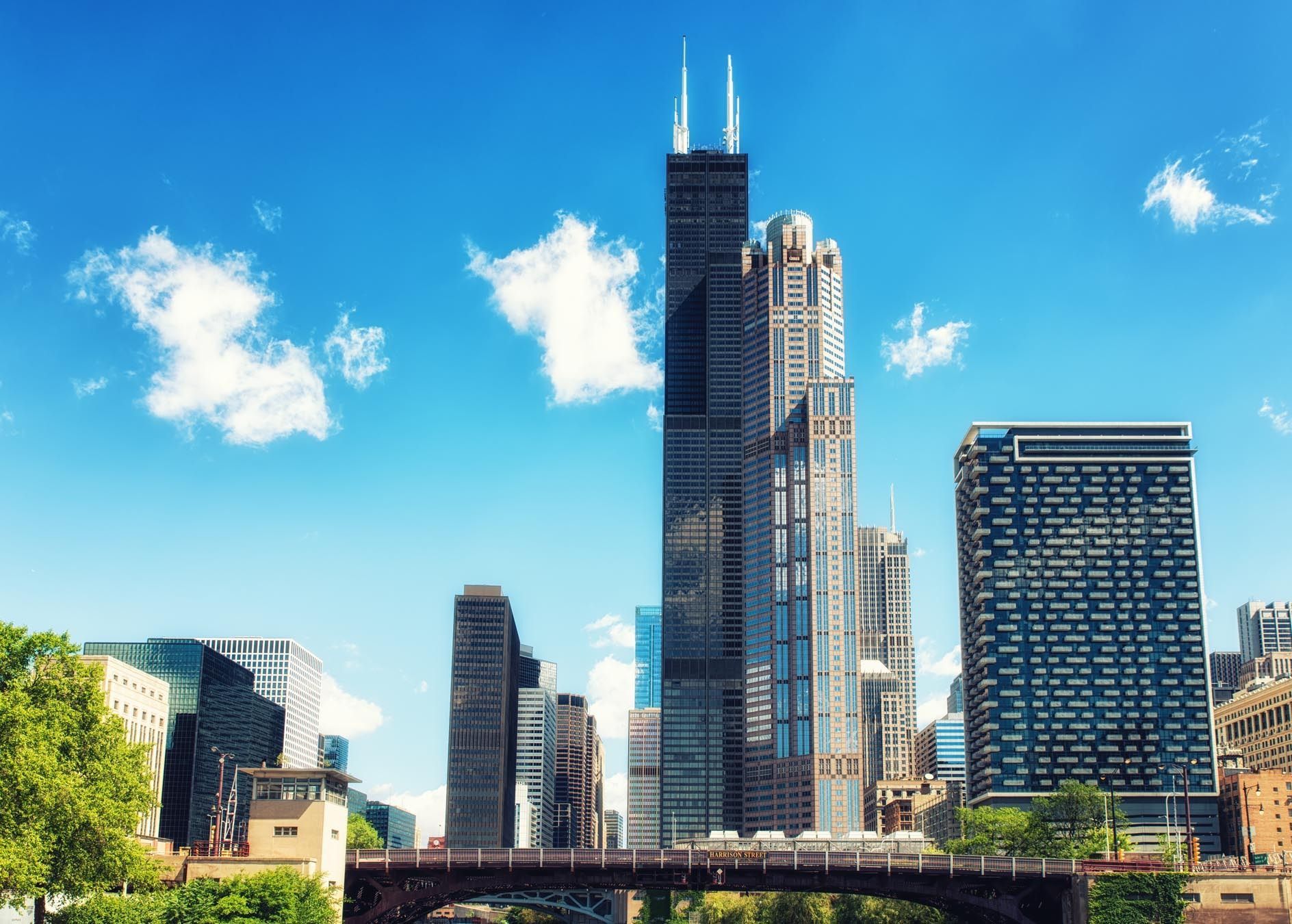 Chicago skyline with Willis Tower and other skyscrapers against a blue sky with fluffy clouds.