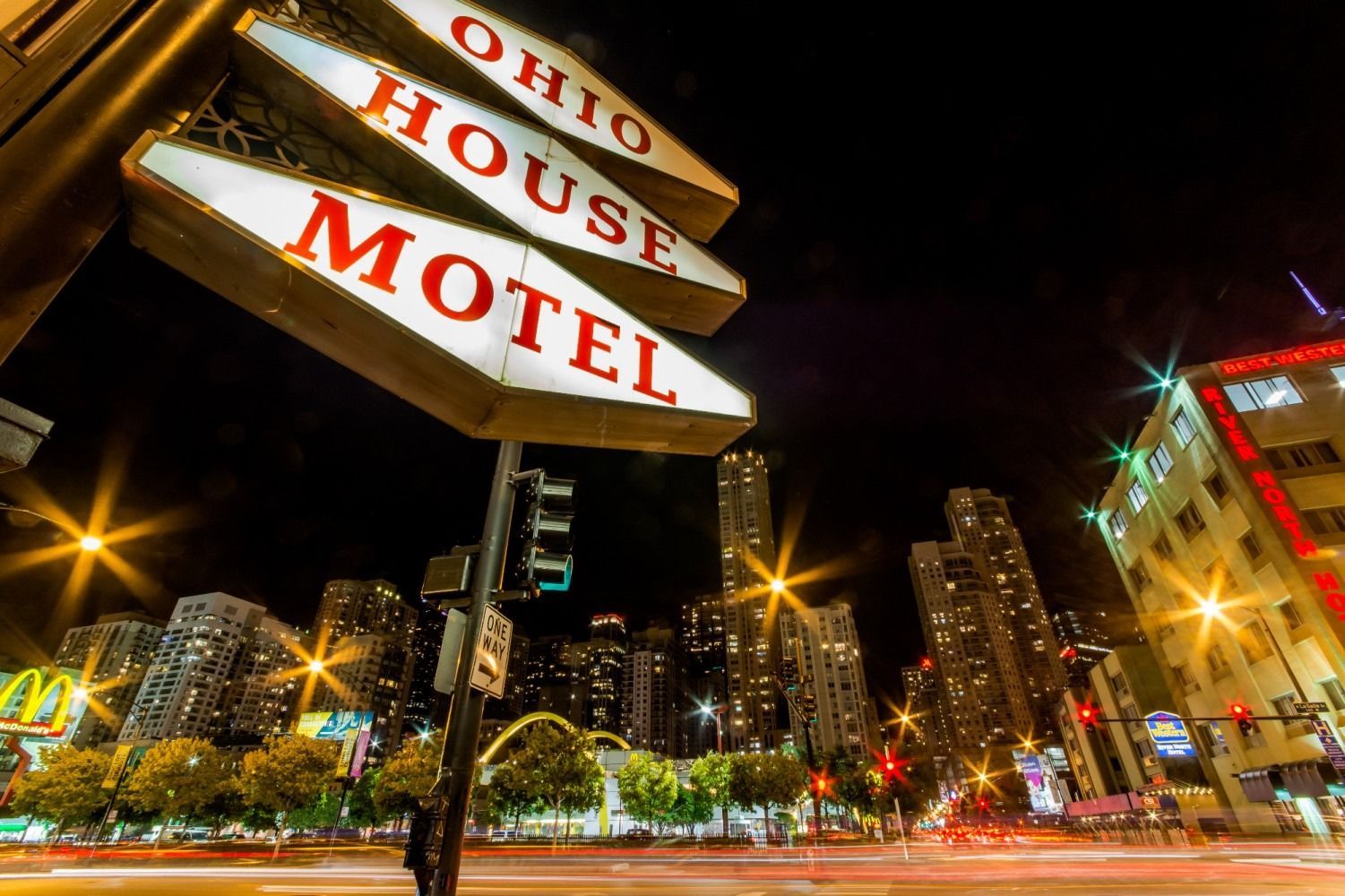 Ohio House Motel sign at night, street view with city buildings and lights.