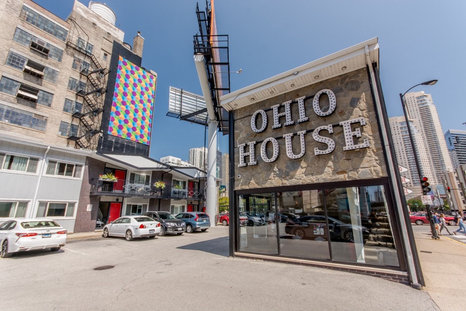 Ohio House sign with a building, cars, and a billboard on a sunny day.