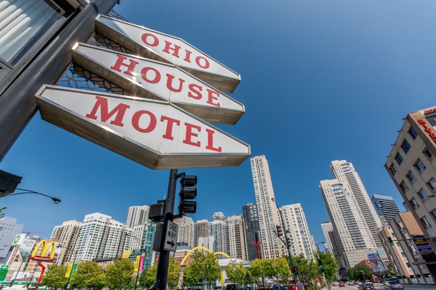 Sign for Ohio House Motel with city skyline in background.