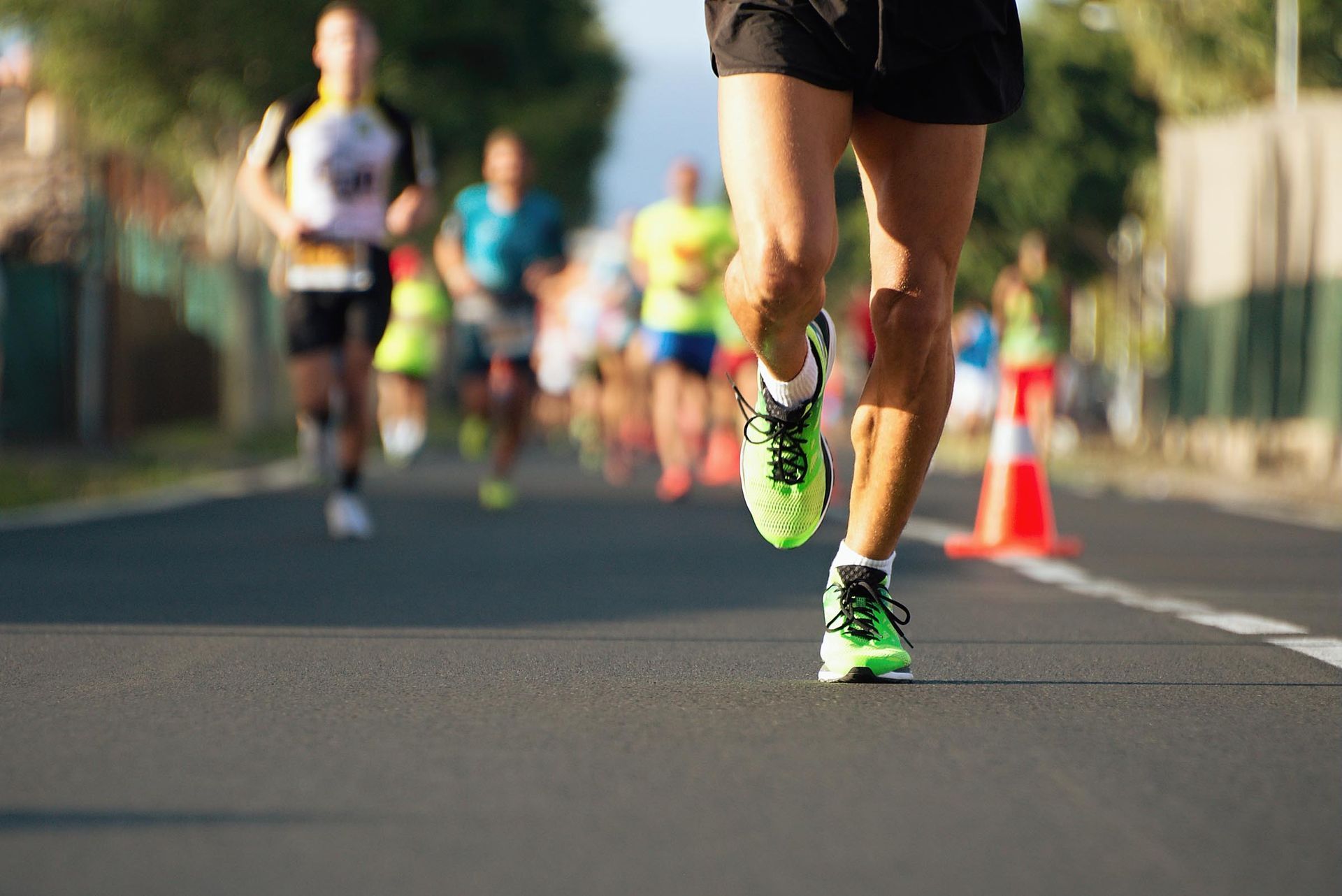Runners in neon green shoes on a paved road, blurred background.