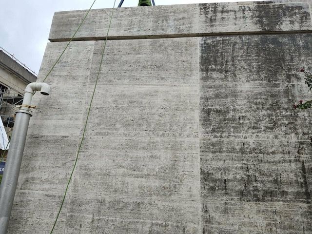 Gray concrete wall with water stain, pipe, and cable.