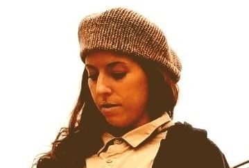 Donna con un cappello di lana grigio che guarda in basso su uno sfondo luminoso