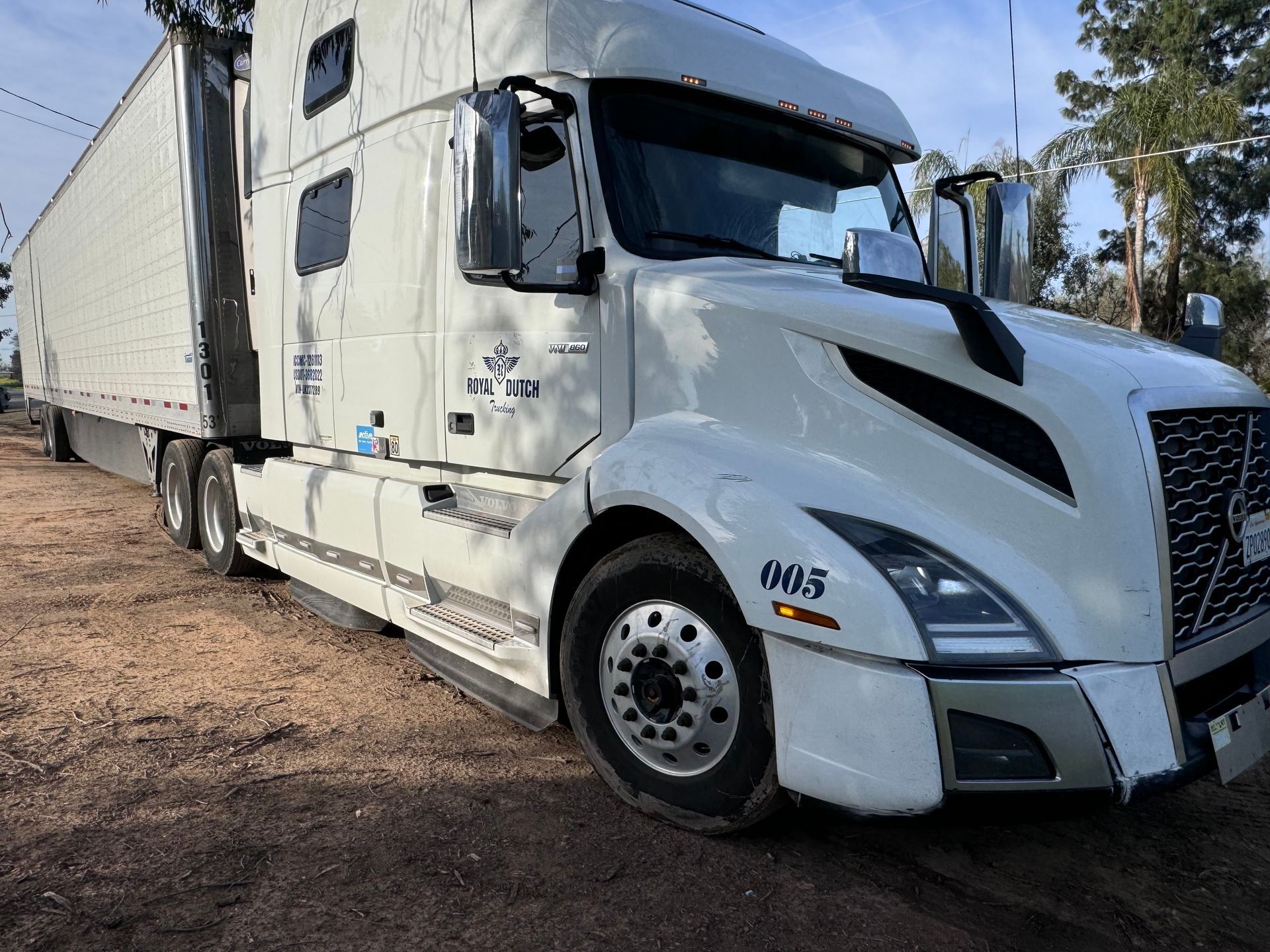 White semi-truck parked outdoors. Shows the front of the truck and the attached trailer.