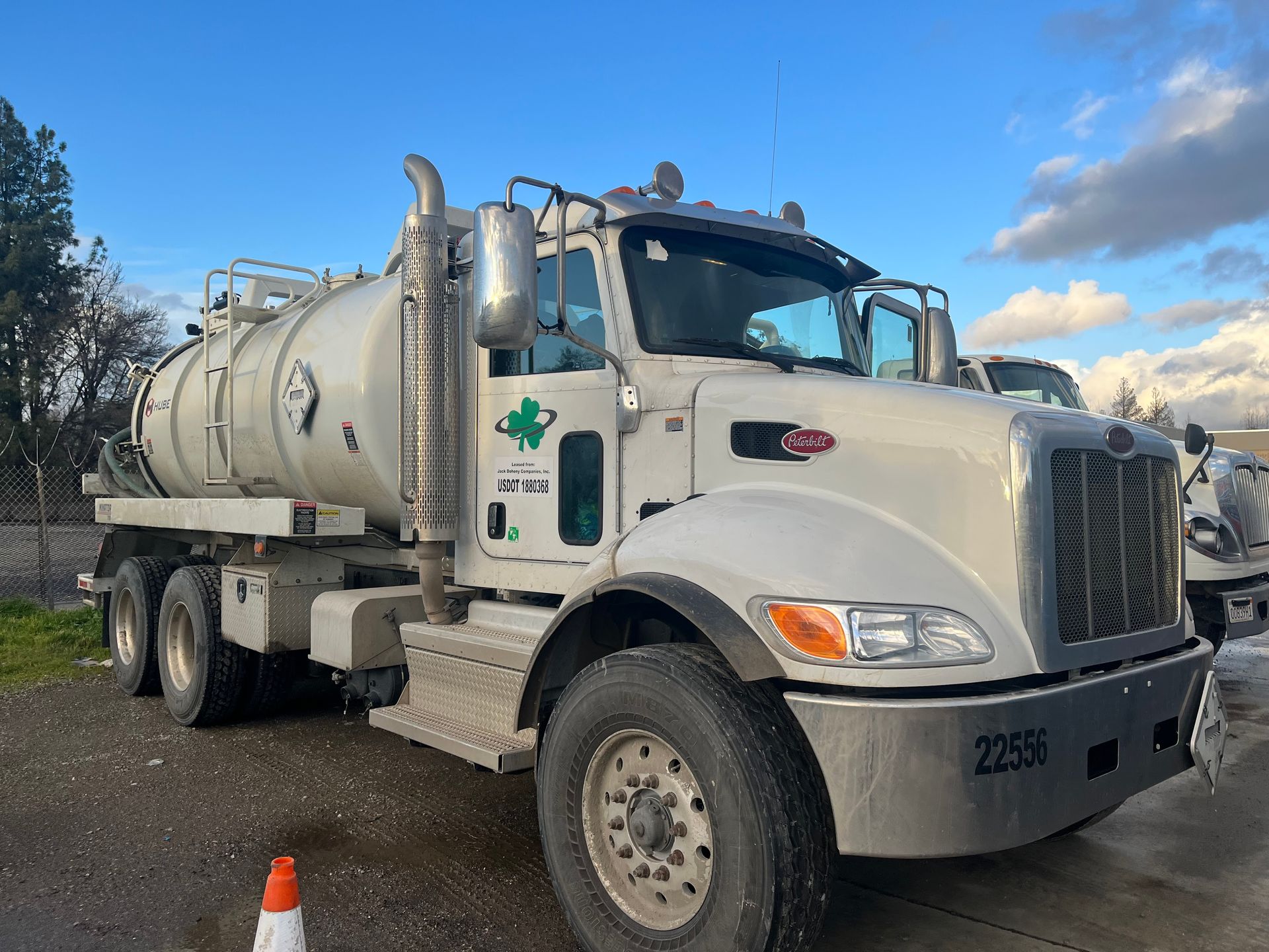 White septic truck parked outdoors on a cloudy day.