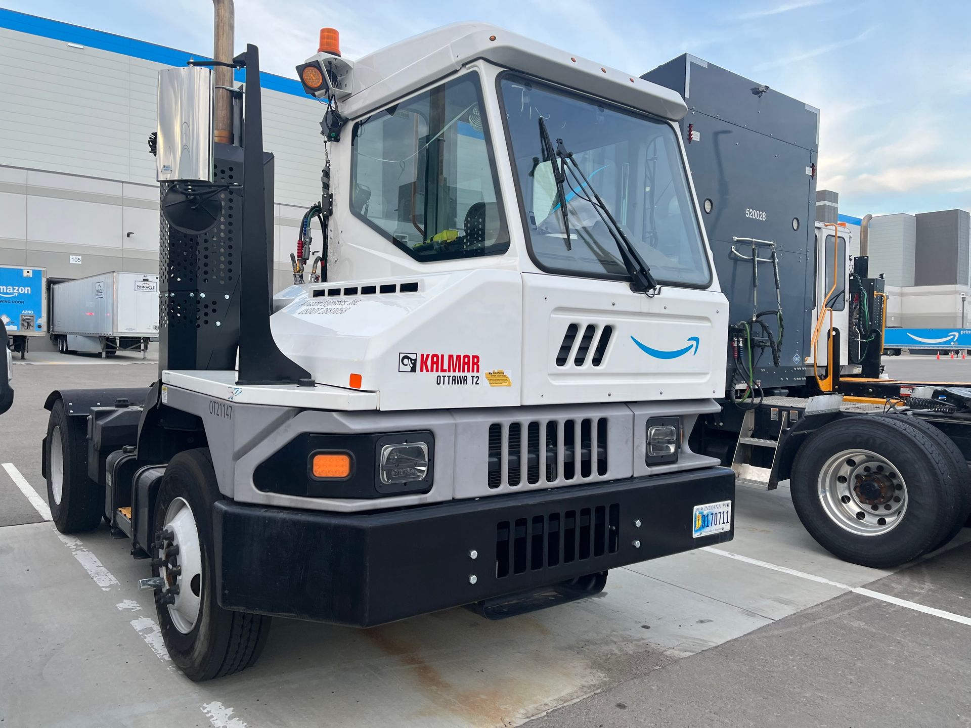 White Amazon yard truck, parked outdoors in a loading dock area.