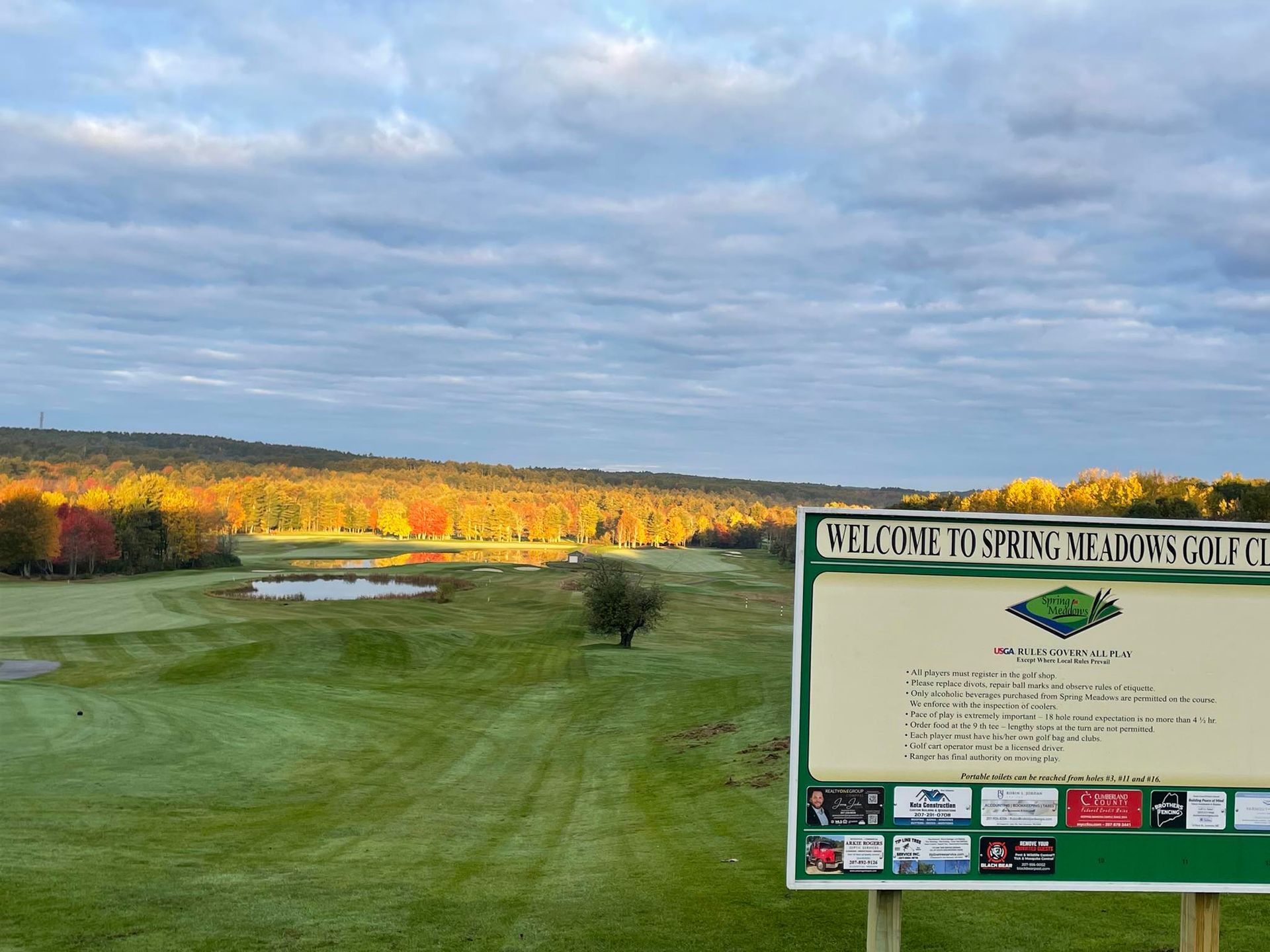 A golf course with a welcome sign in the foreground