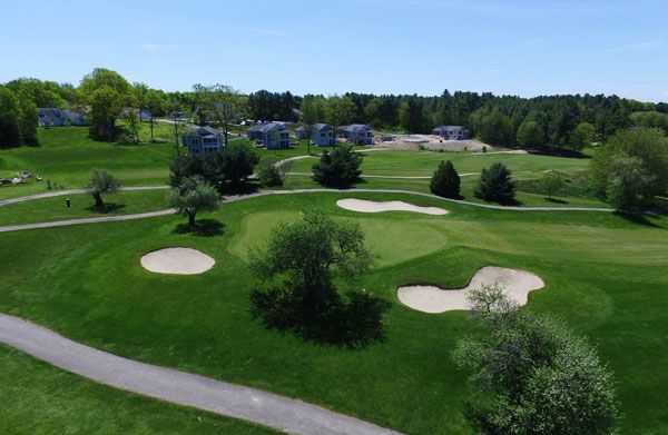 An aerial view of a residential area with a tennis court and a golf course.