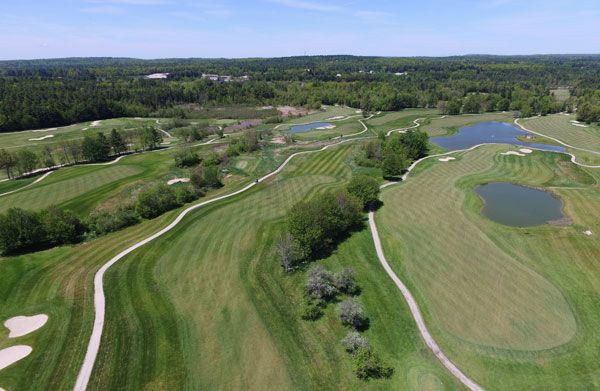 An aerial view of a golf course surrounded by trees and water.