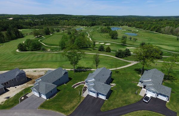 An aerial view of a golf course with houses in the foreground.
