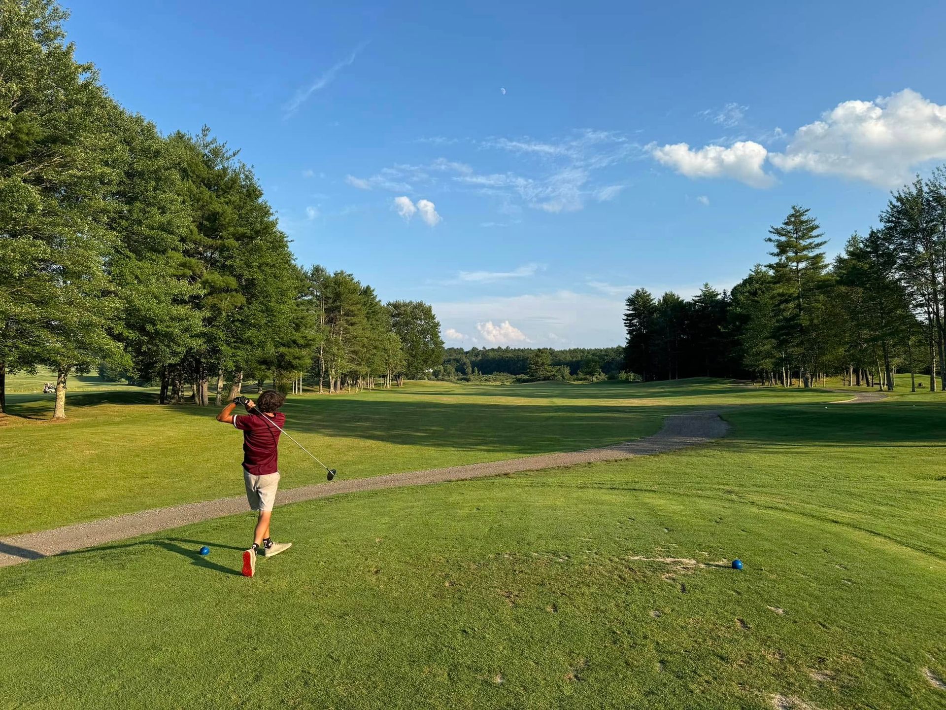 A man is swinging a golf club on a golf course.