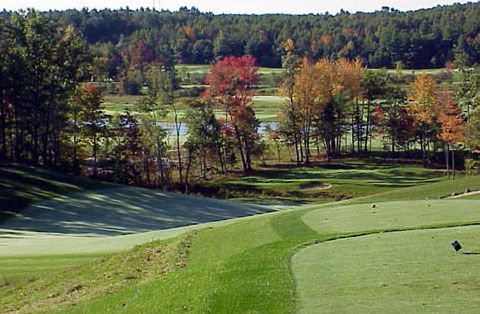 A golf course with trees and a lake in the background