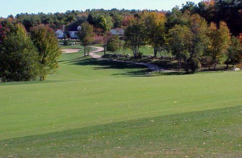 A golf course with trees and houses in the background