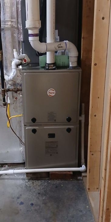 Furnace in a utility room with white PVC piping.