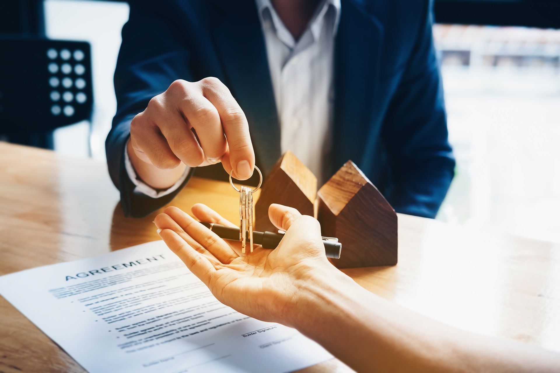 A cropped view of a lawyer handing a key to a buyer, symbolizing the completion of a home purchase. A cropped view of a lawyer handing a key to a buyer, symbolizing the completion of a home purchase.
