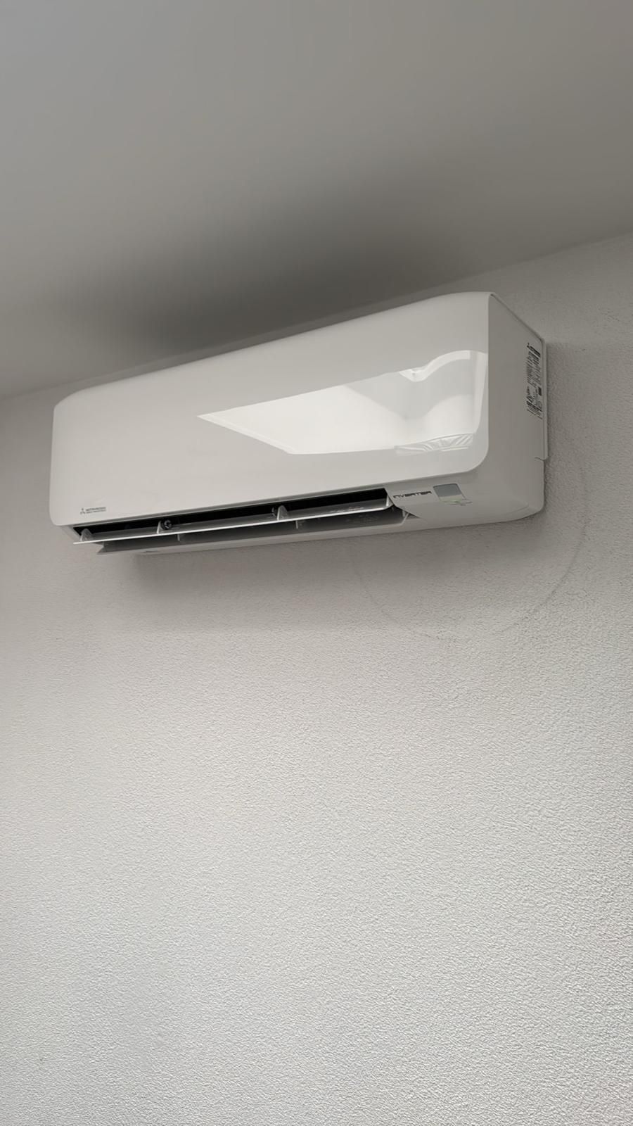 Witte wandairconditioner op een lichtgrijze muur.