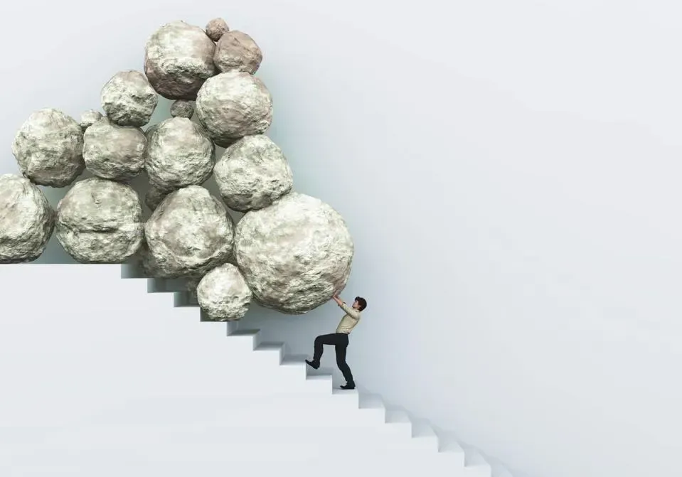 A man is pushing a pile of rocks up a set of stairs.