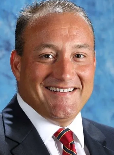 A man in a suit and tie is smiling for the camera