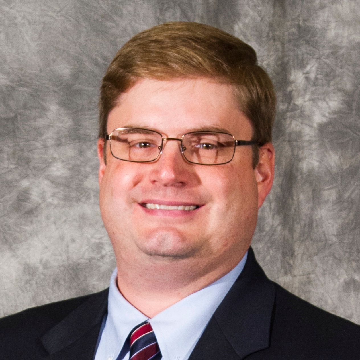 A man in a suit and tie is smiling for the camera