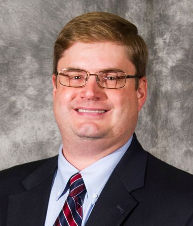 A man in a suit and tie is smiling for the camera