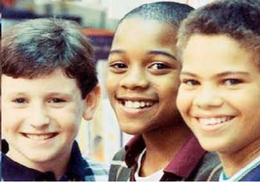 Three young boys are smiling for the camera while standing next to each other.