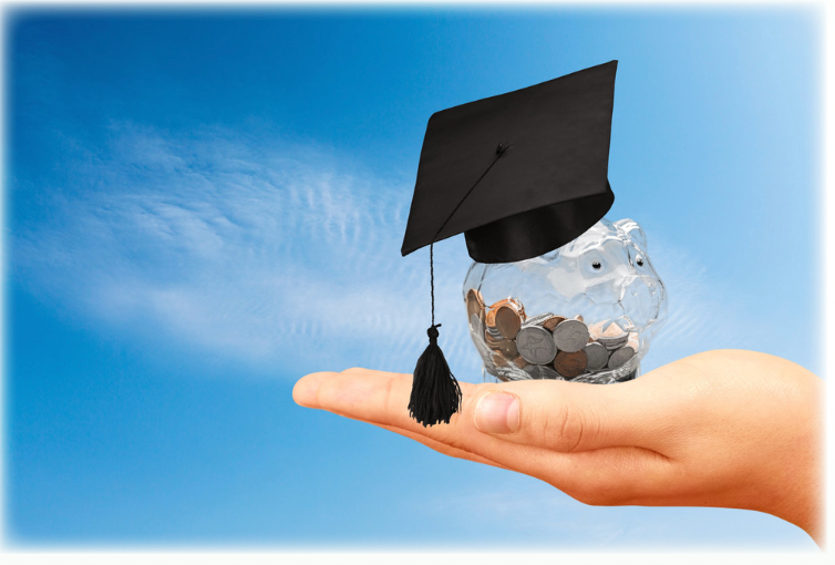 A hand holding a piggy bank with a graduation cap on it