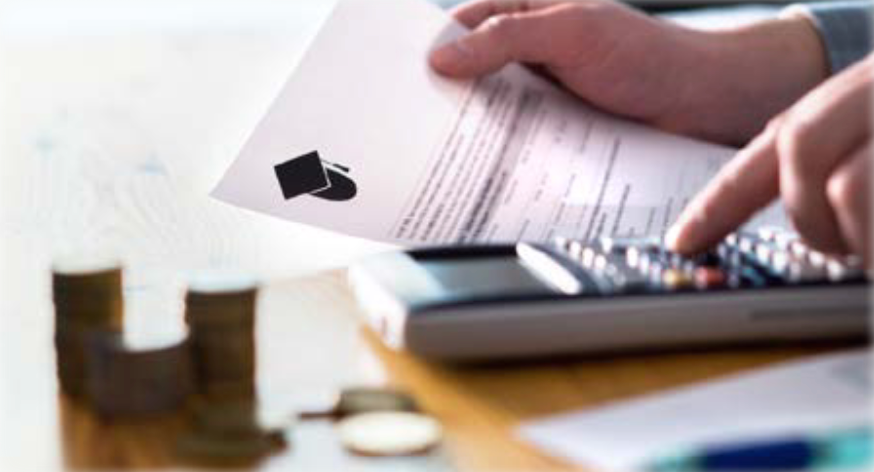 A person is using a calculator while holding a piece of paper with a graduation cap on it.
