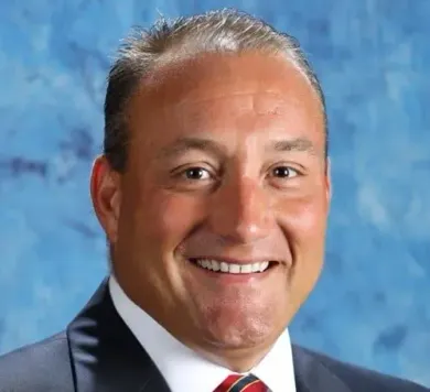 A man in a suit and tie is smiling for the camera