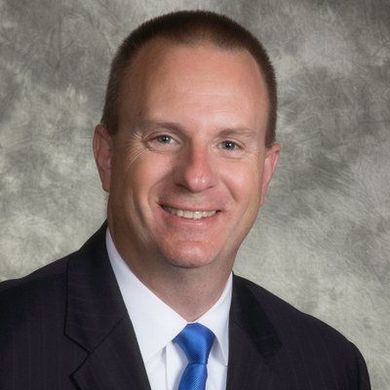 A man in a suit and tie is smiling for the camera
