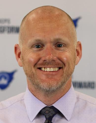 A bald man with a beard is smiling for the camera