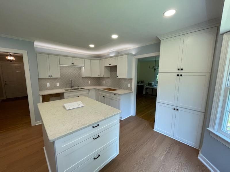 Newly renovated kitchen with white cabinets, island, and wood flooring.