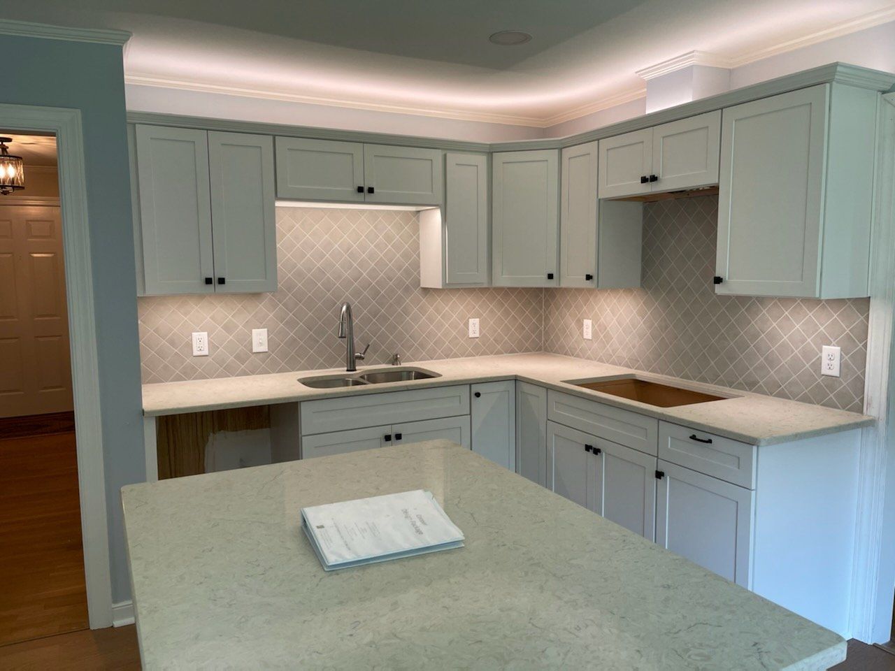 White kitchen with island and cabinets; tile backsplash, under-cabinet lighting.