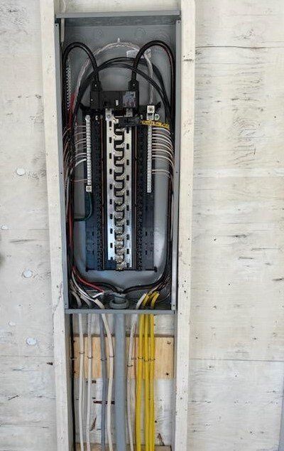 Electrical panel with wires and breakers installed in a wall.