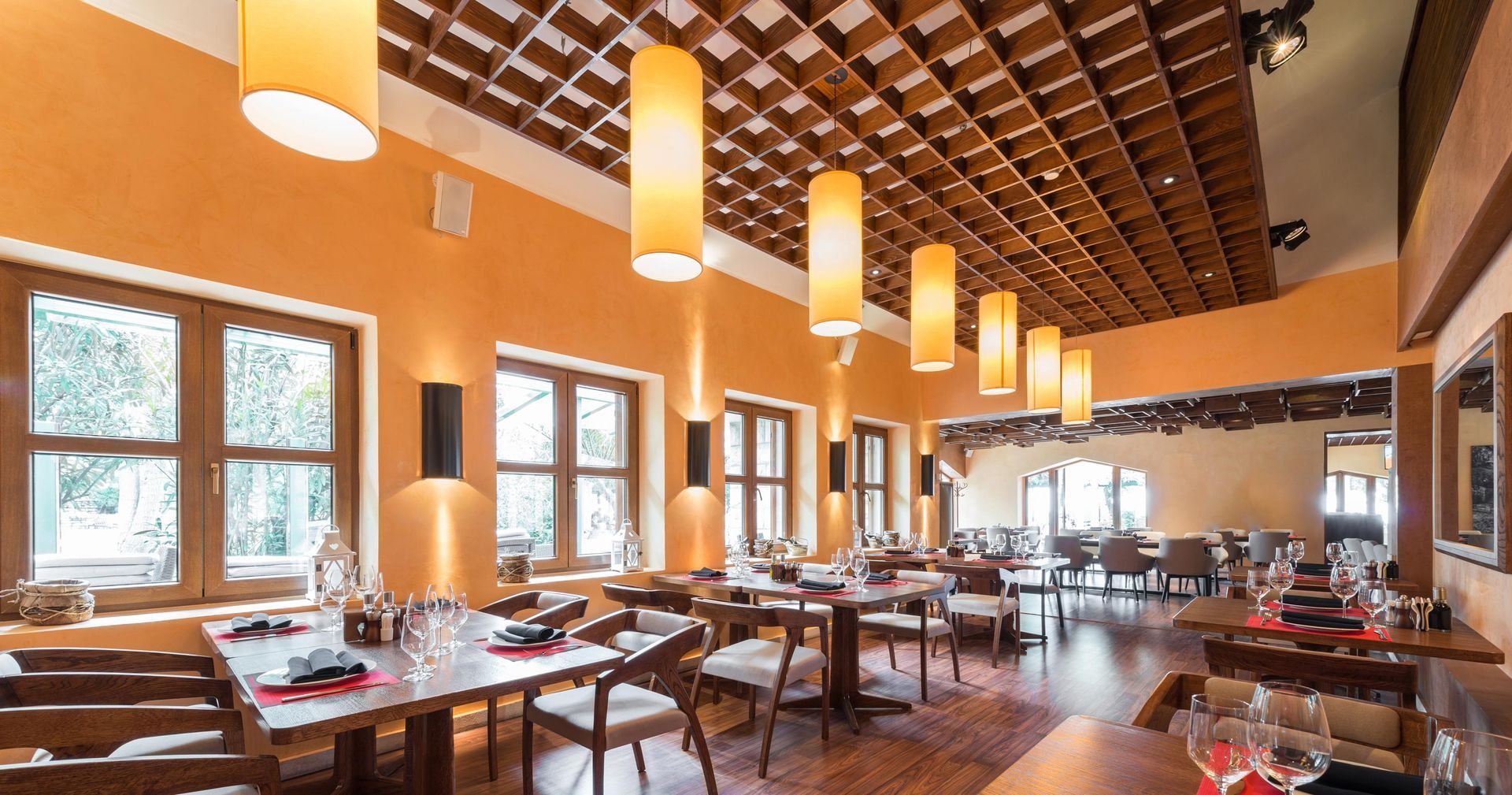 Restaurant interior with orange walls, wooden tables, chairs, and hanging pendant lights. Restaurant interior with orange walls, wooden tables, chairs, and hanging pendant lights.