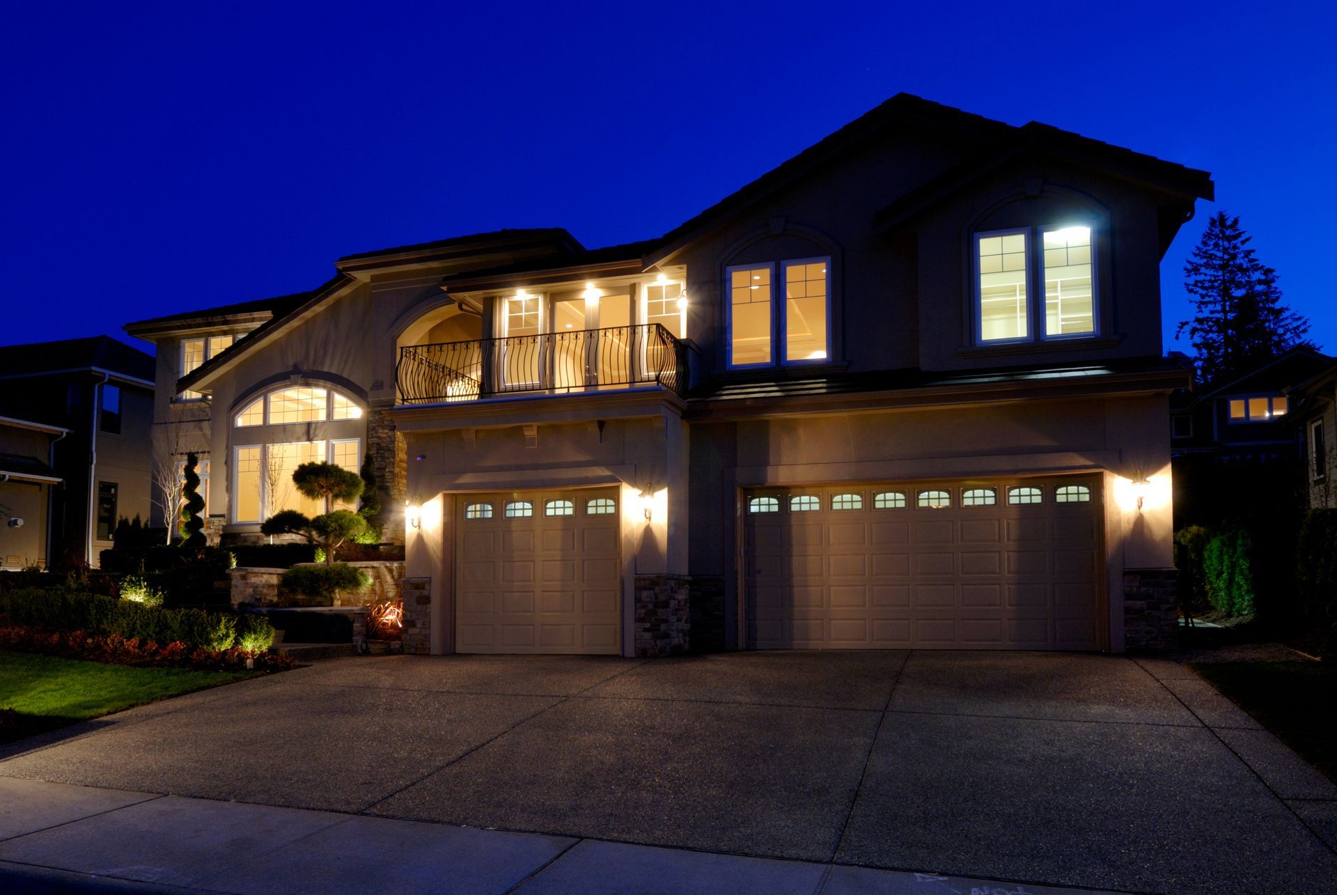 Two-story house at night with illuminated windows and garage, under a dark blue sky. Two-story house at night with illuminated windows and garage, under a dark blue sky.