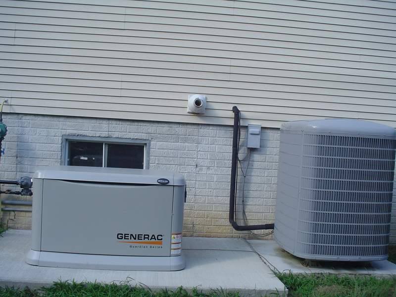A Generac generator next to a house, with a central air unit and concrete slab.