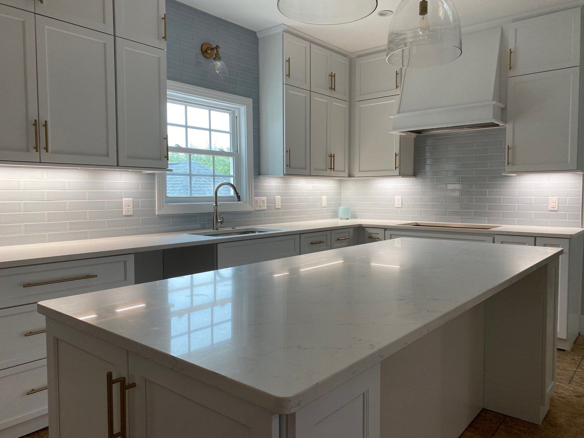 Modern white kitchen with island, cabinets, and tile backsplash.