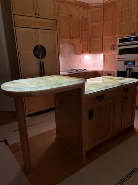 A kitchen with wooden cabinets and a marble counter top