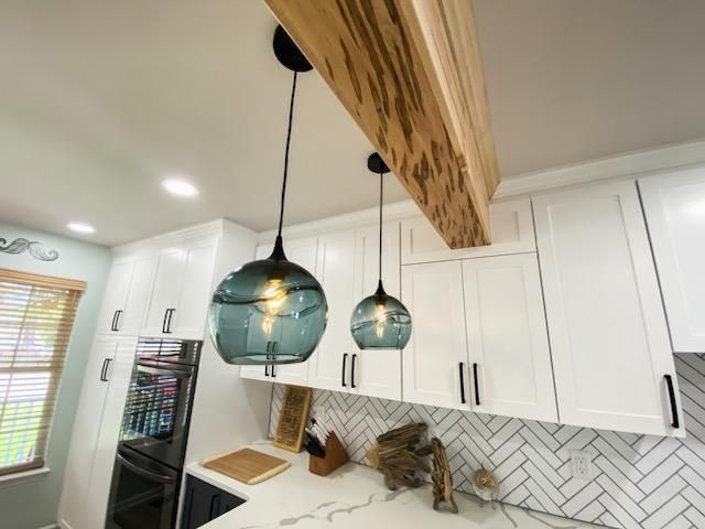 A kitchen with white cabinets and a wooden beam hanging from the ceiling.