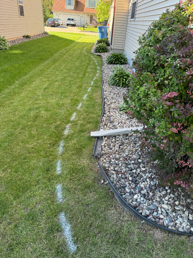 A lawn with white lines drawn on it and a house in the background.