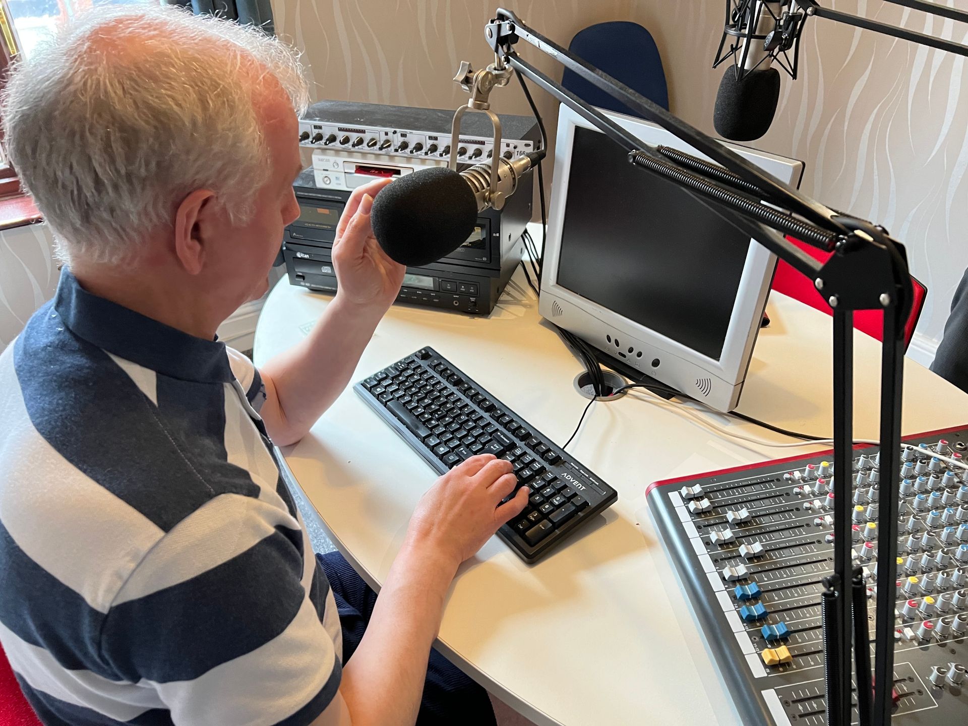 Philip Anderson speaks into his microphone, surrounded by other audio recording equipment. 