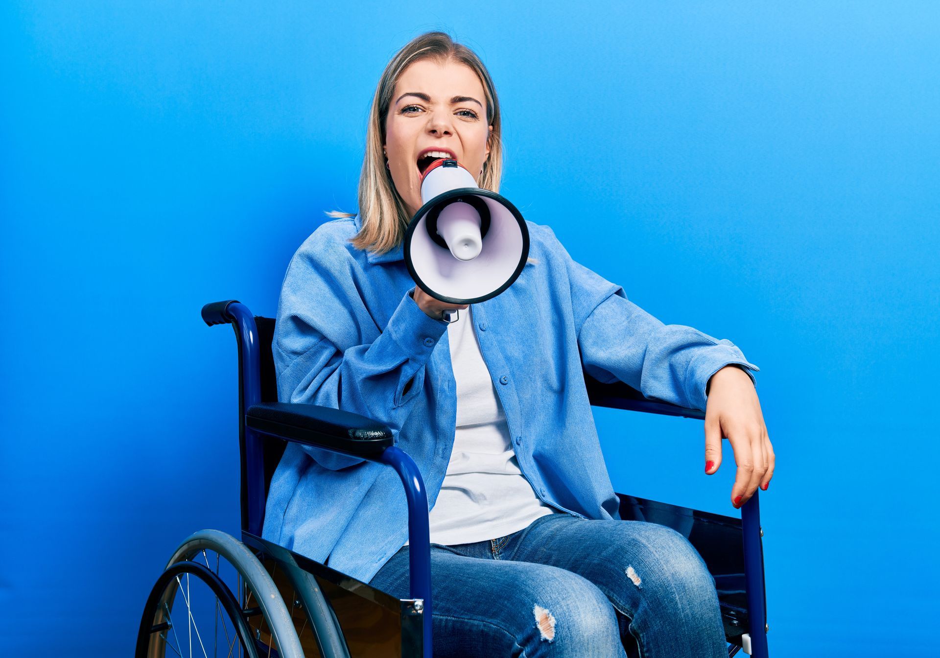 A woman in a wheelchair shouts into a megaphone, expressing her views with enthusiasm.