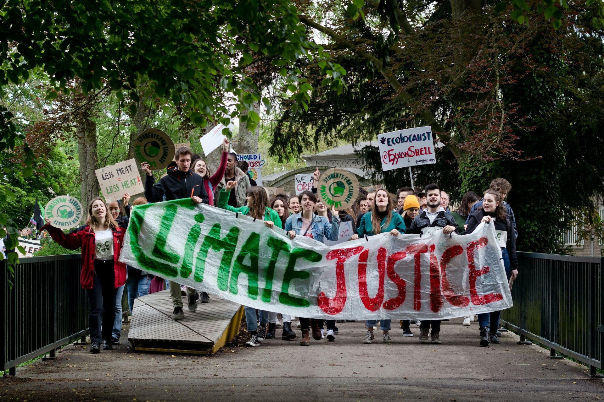 A large crowd of climate activists march forward, led by a group clutching at a banner declaring ‘climate justice.’