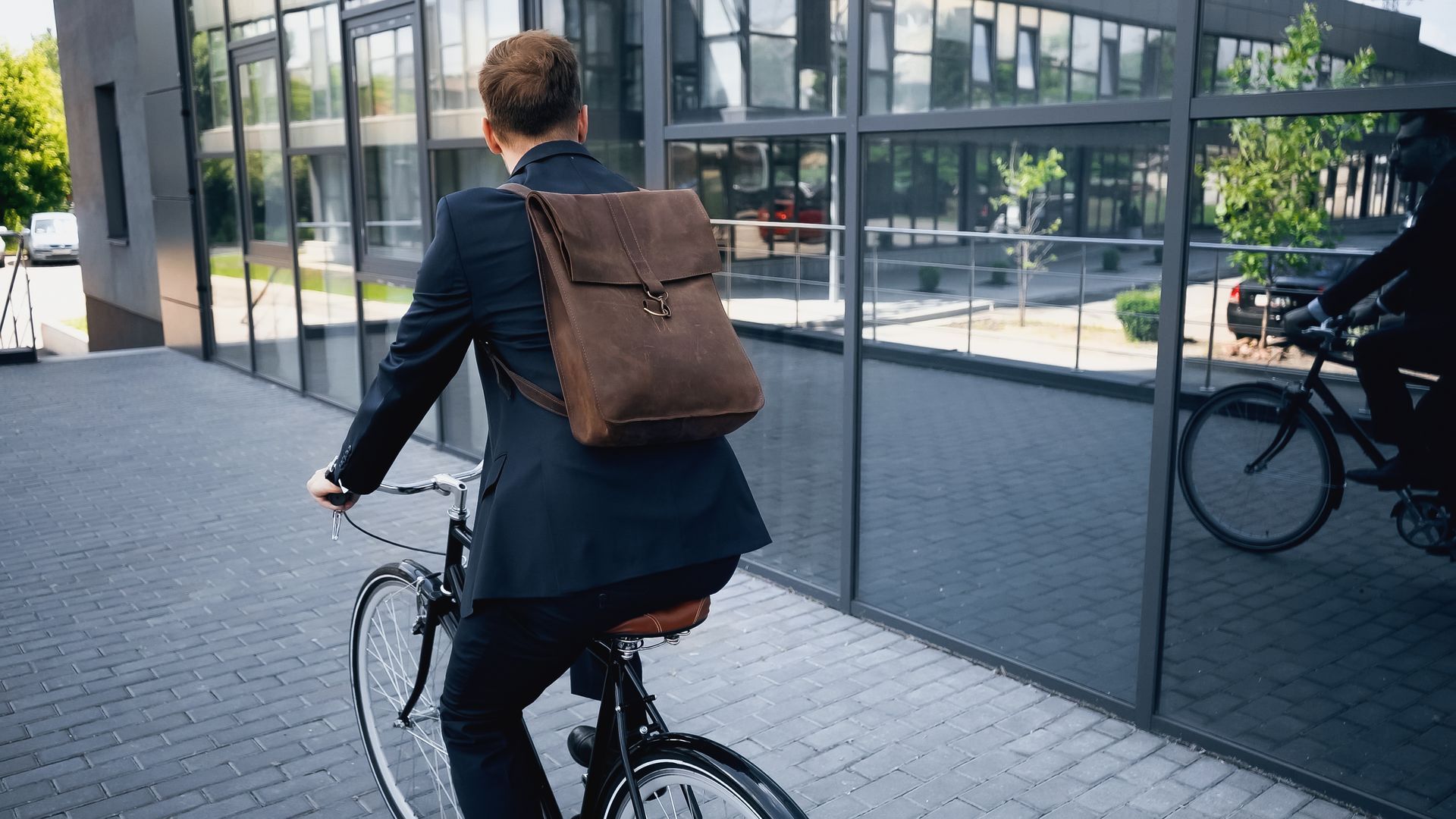 A young businessman in a smart suit cycles to work.