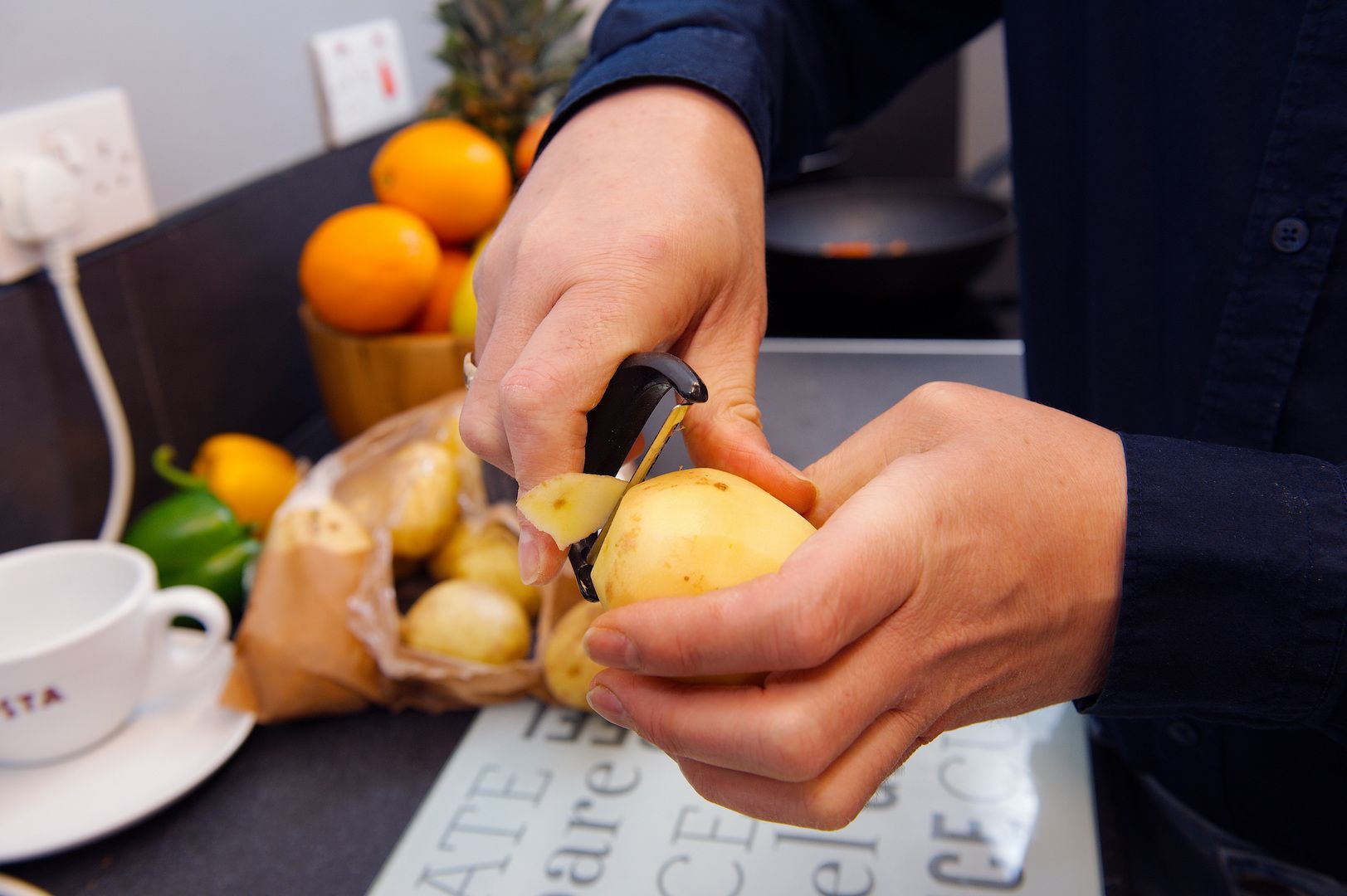 Philip Anderson peeling a potato using a standard potato peeler.