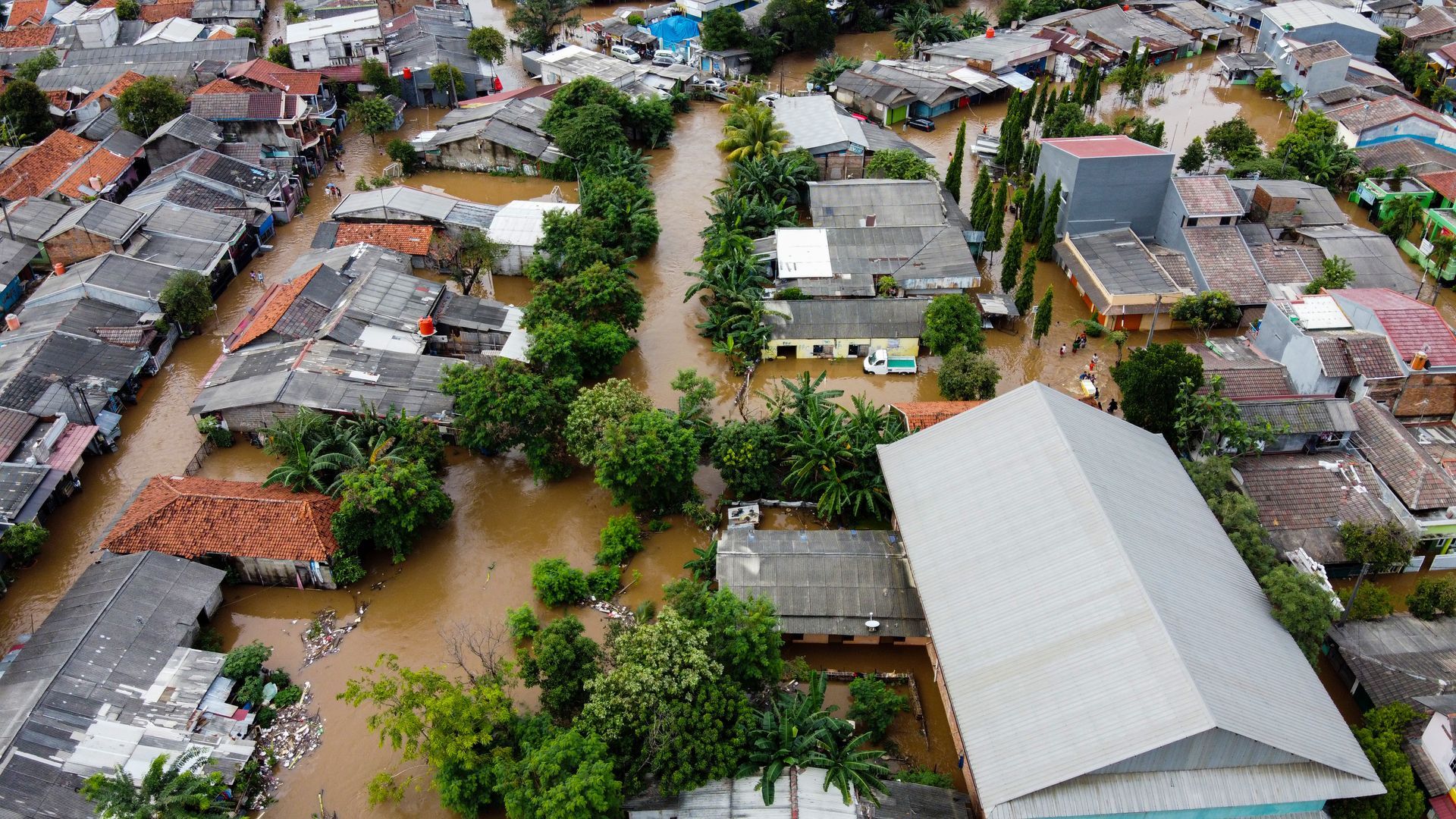 An aerial view of a town half-submerged in thick, muddy water.