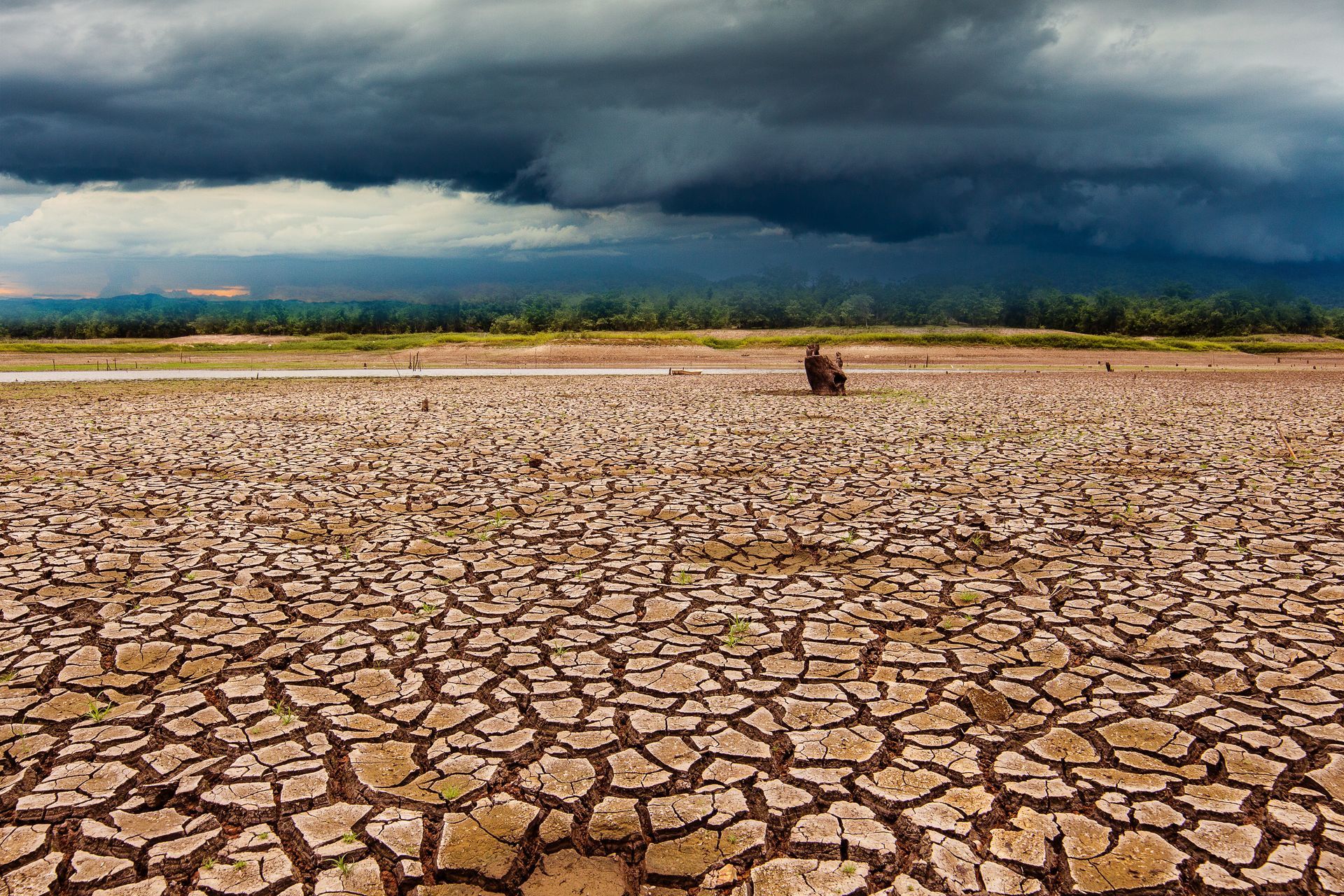 A storm cloud rolls over a dry and cracked landscape.